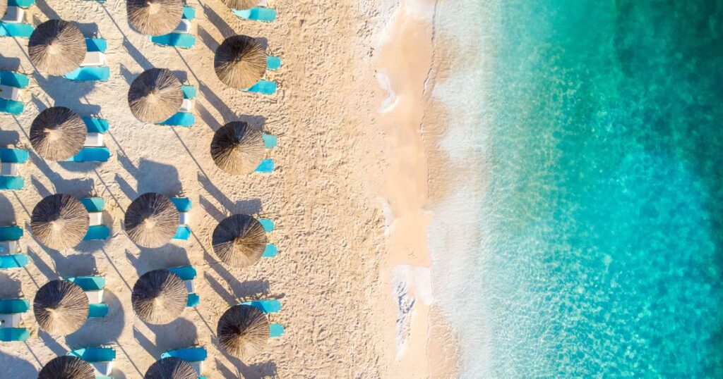 luchtfoto van zandstrand op eiland Thassos met ligbedjes en rietenparasols